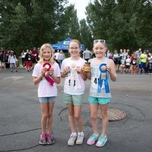 3 young femail participants of the Stampede 5K Race & 2-Mile Fun Walk at the Colorado State Fair & Rodeo pose with their ribbons.