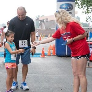 A young girl and her dad receiving ribbons after the Stampede 5K Race & 2-Mile Fun Walk at the Colorado State Fair & Rodeo.