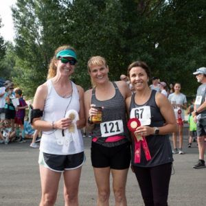 3 female participants of the Stampede 5K Race & 2-Mile Fun Walk at the Colorado State Fair & Rodeo pose with their ribbons.