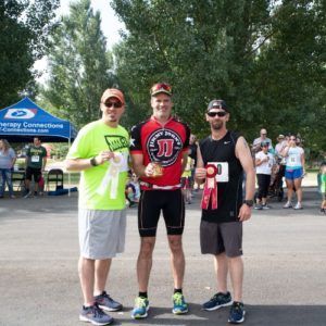 3 male participants of the Stampede 5K Race & 2-Mile Fun Walk at the Colorado State Fair & Rodeo pose with their ribbons.