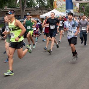 Man in a yellow shirt leads the pack of runners during the Stampede 5K Race at the Colorado State Fair & Rodeo!