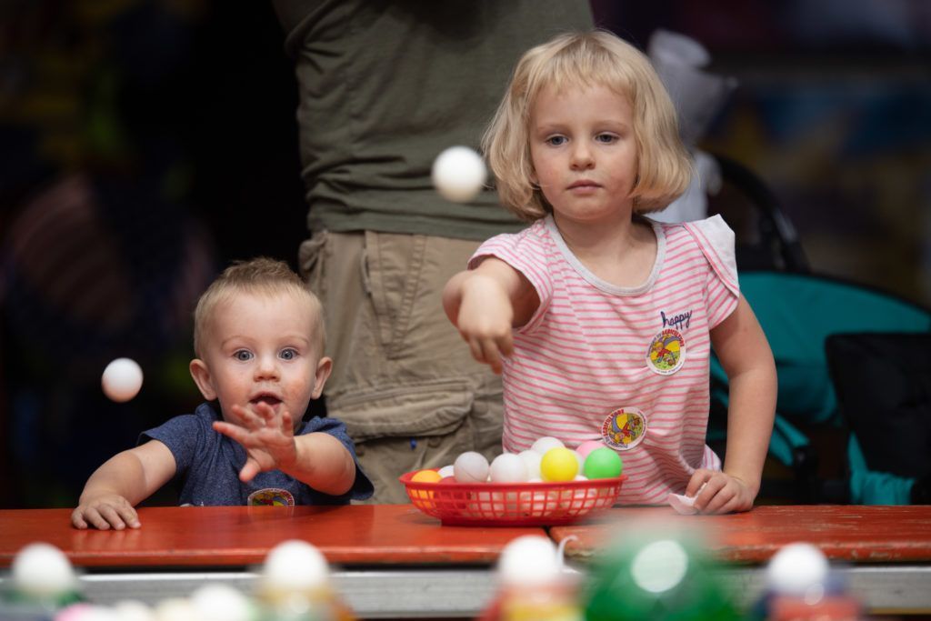two young children throwing white balls in a carnival game at the Colorado State Fair