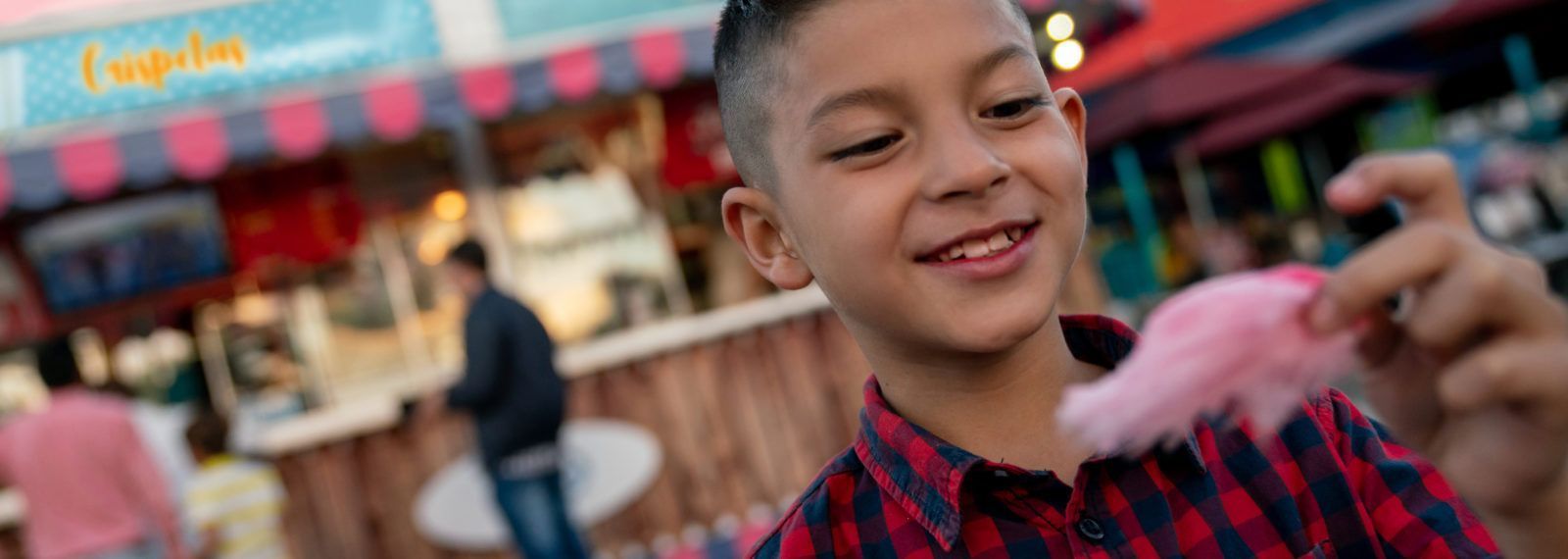 Happy boy eating a cotton candy at a funfair