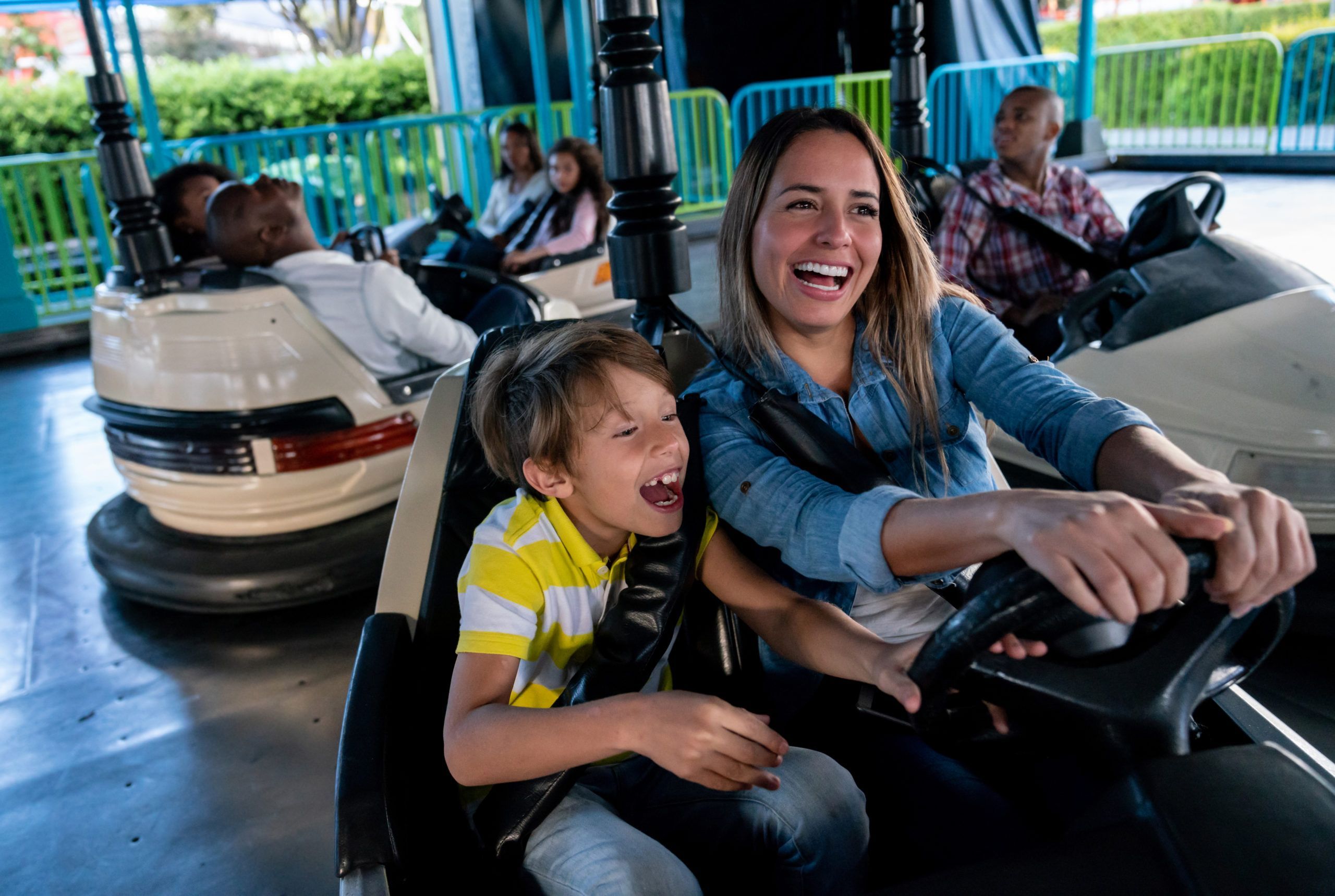 Happy mother and son having fun on the bumper cars at an amusement park - lifestyle concepts