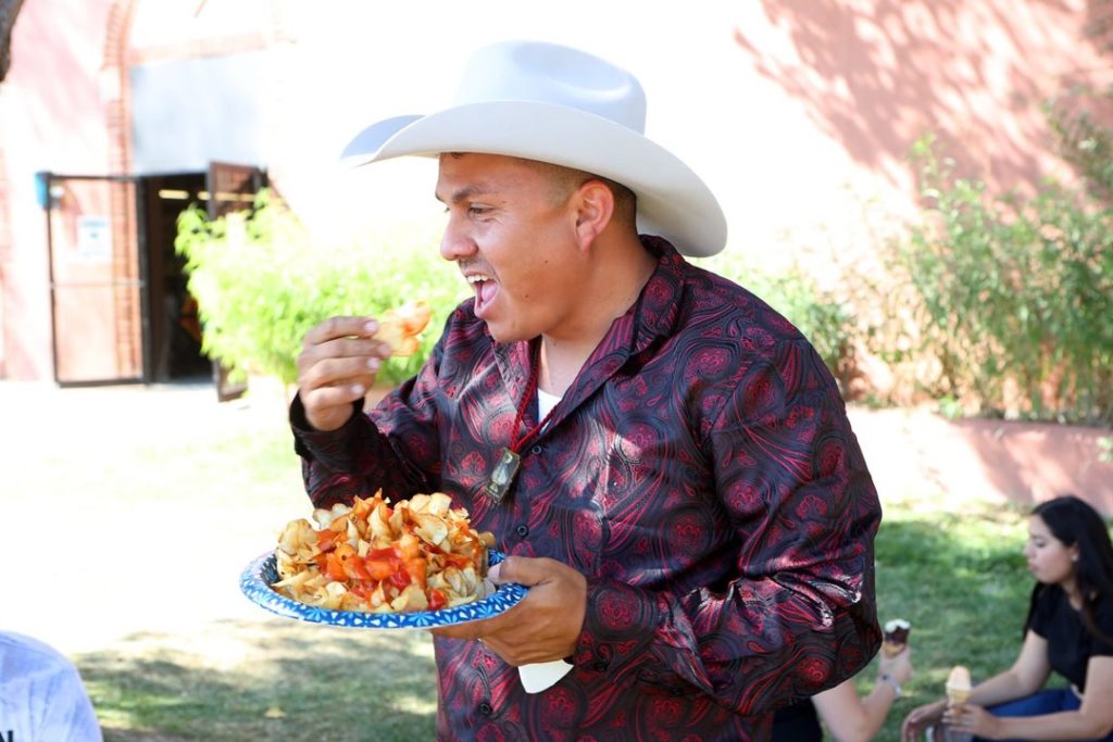 A man in a cowboy hat eating a plate of chips