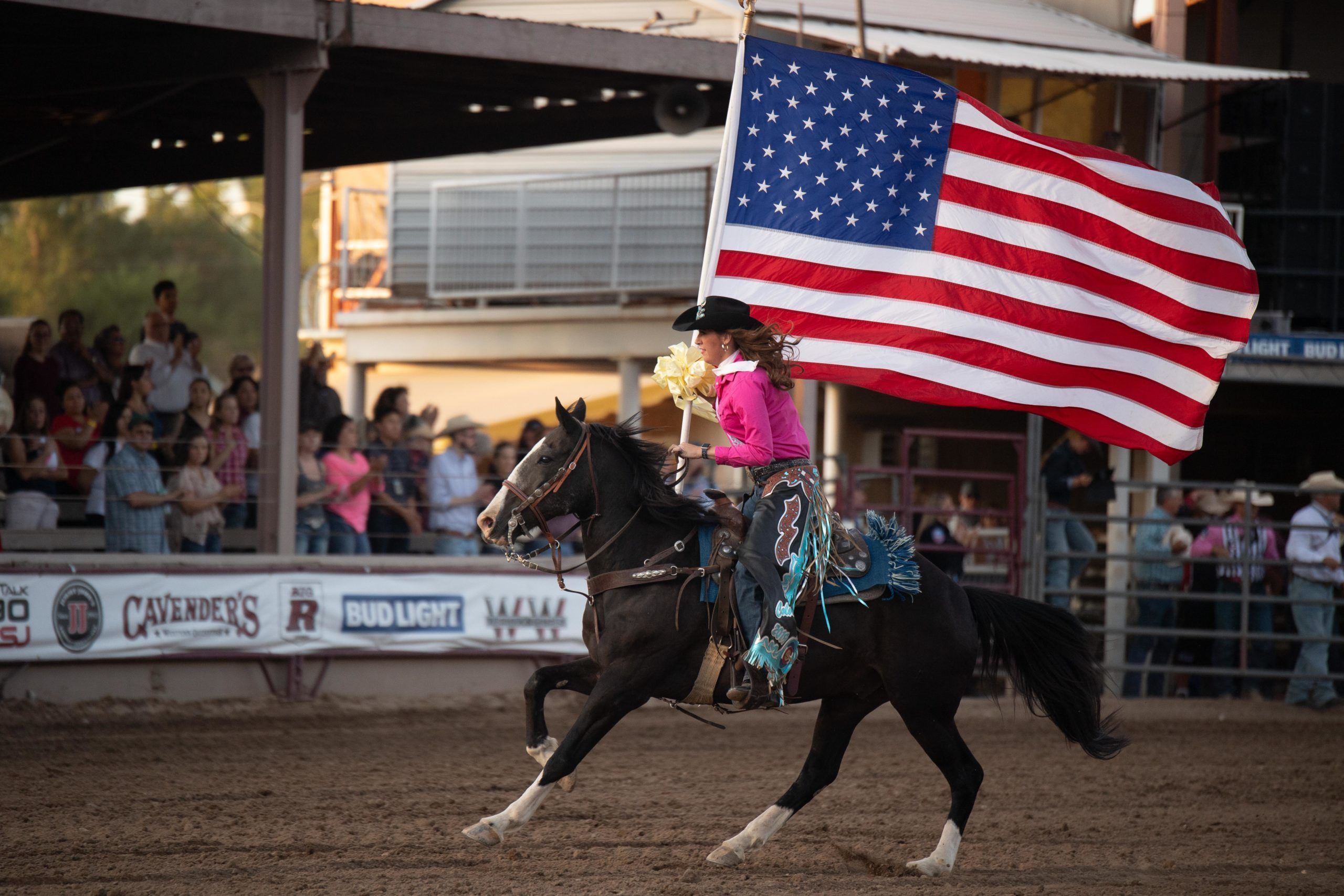girl holds the American flag while riding a horse at the Colorado State Fair