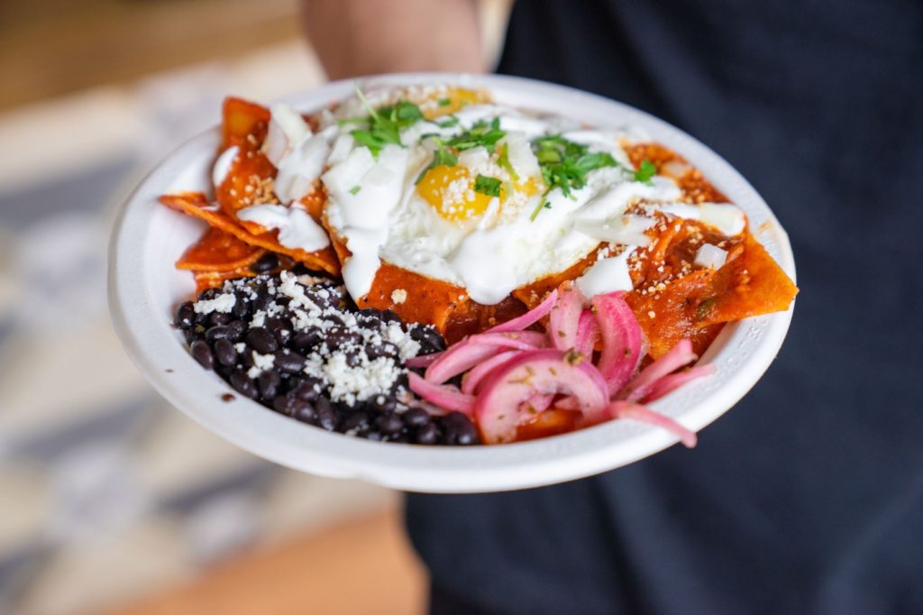 A plate of Chilaquiles, black beans, and red onion 