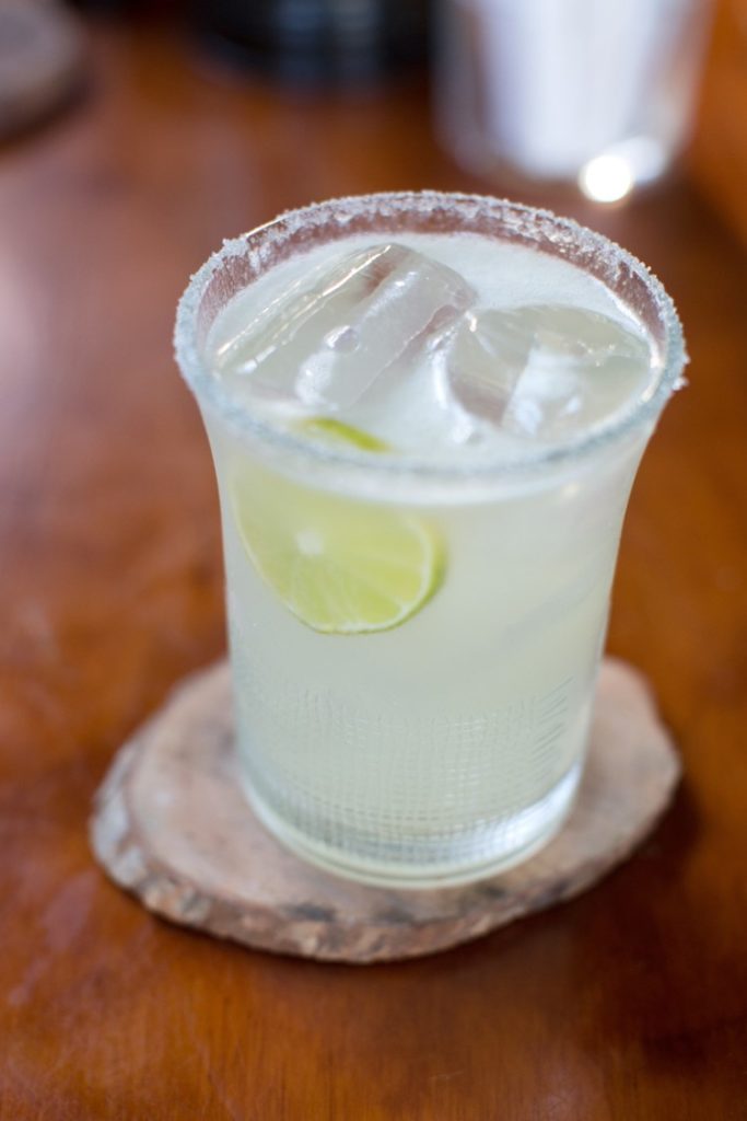 A traditional margarita with lime in a plastic cup with salt on the rim