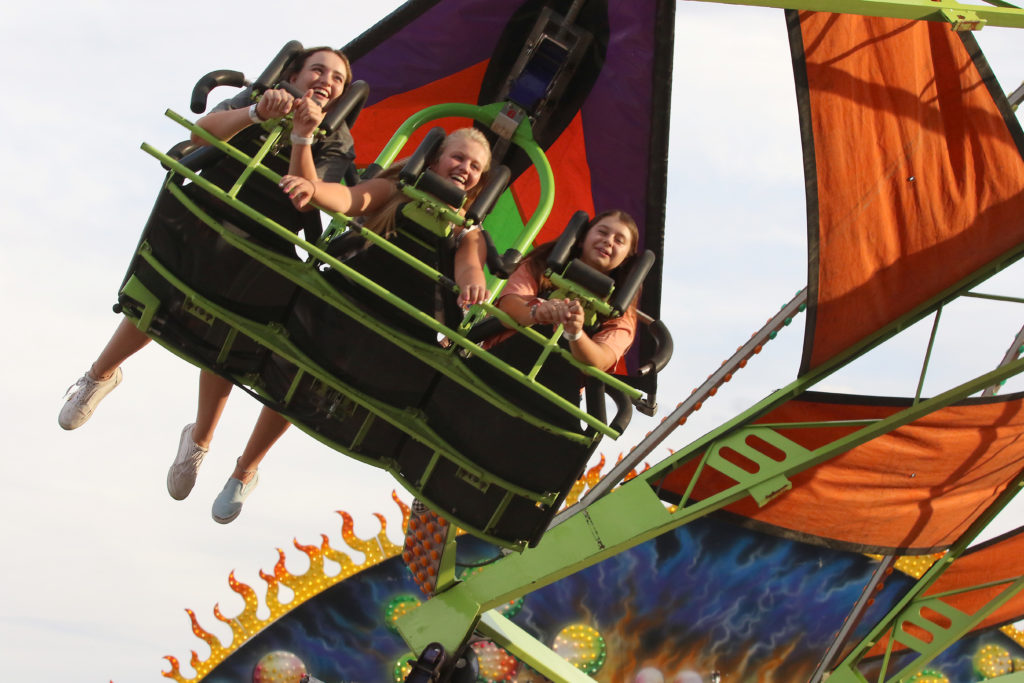Three people on a hangliding themed carnival ride at the Colorado State Fair
