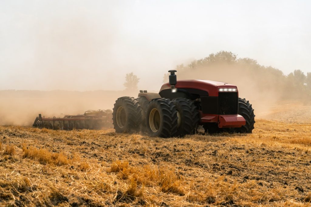 A robotic tractor pulls a combine across a farm field