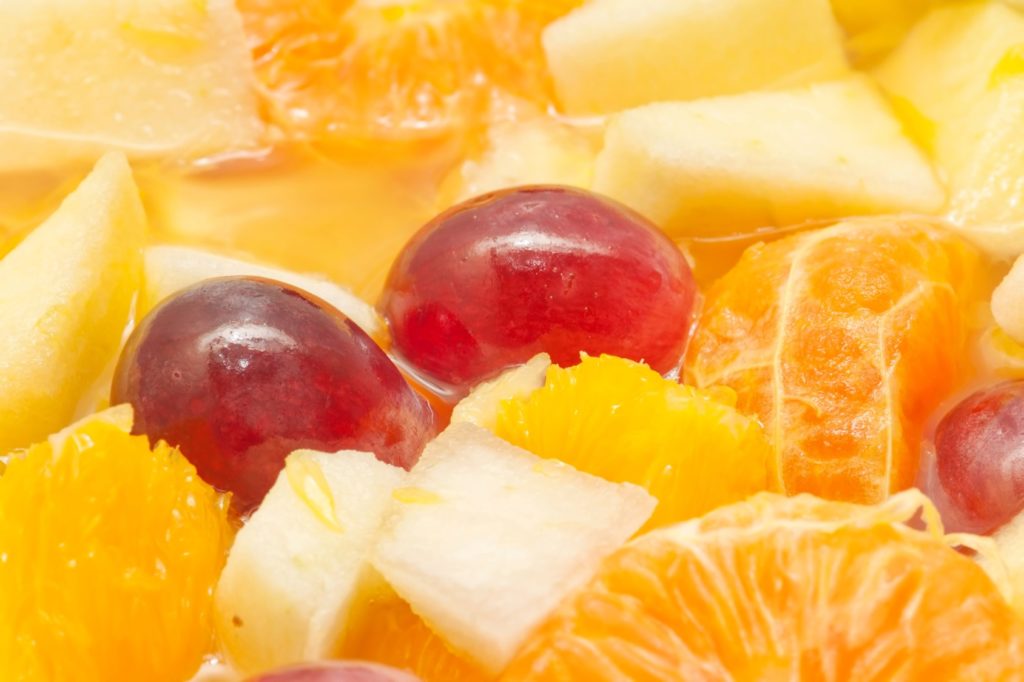 A close up of chopped fruit including grapes, pineapple, and oranges