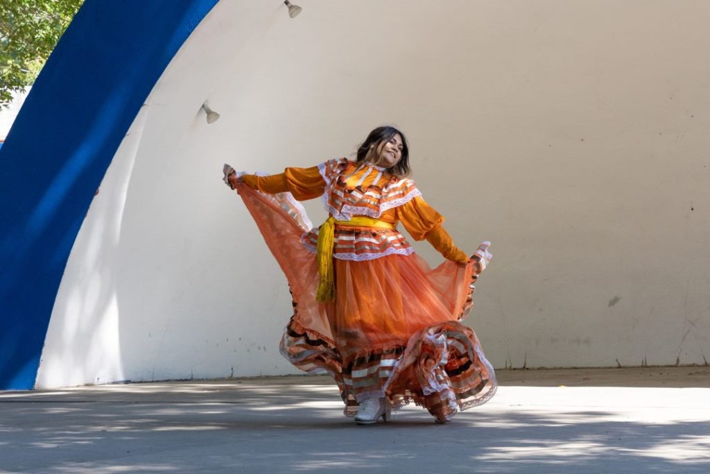 A beautiful woman in traditional Mexican dress dances across a stage at the Colorado State Fair