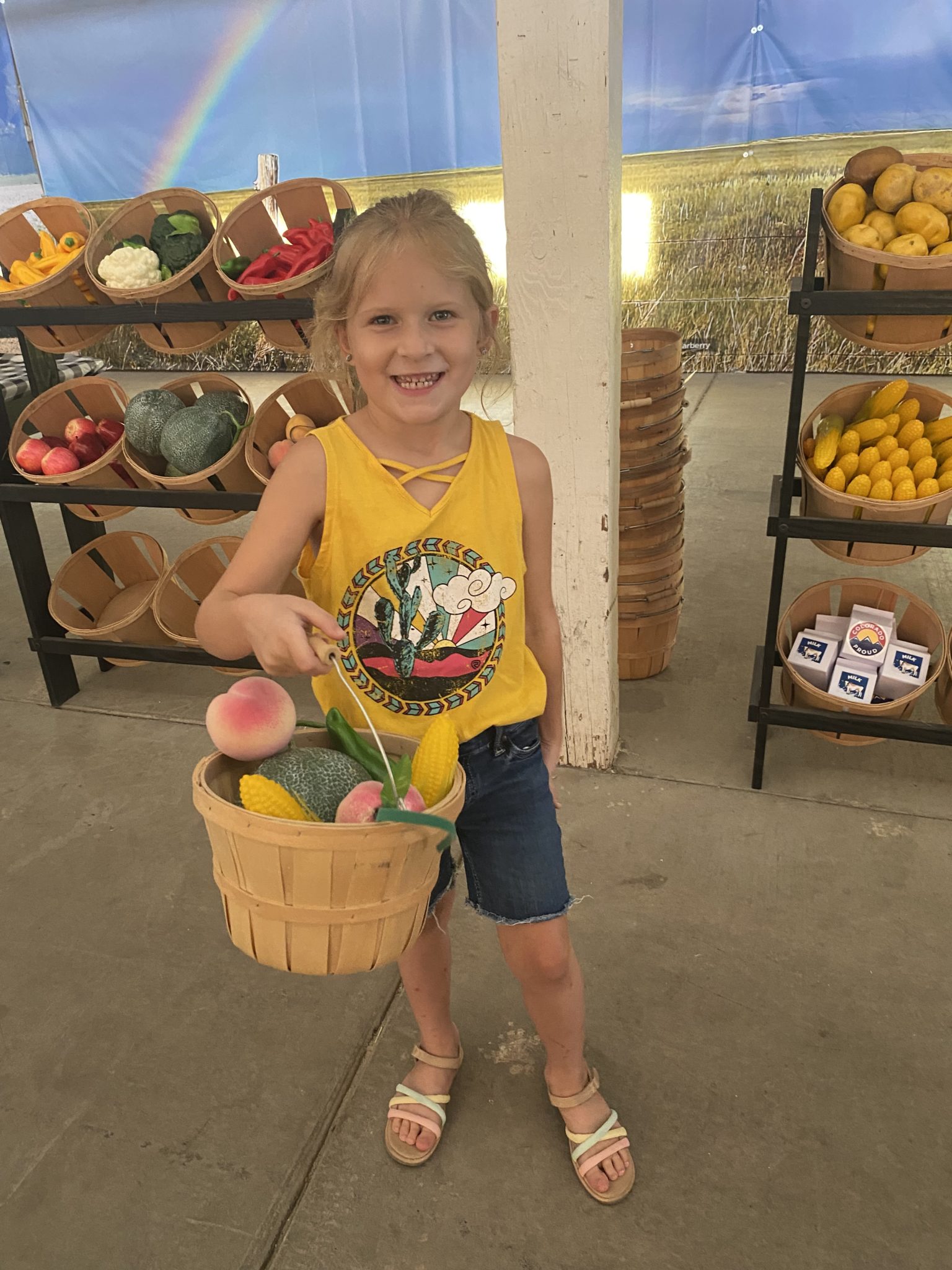 Child holding basket of vegetables and fruit from the Colorado Proud Farm Trail