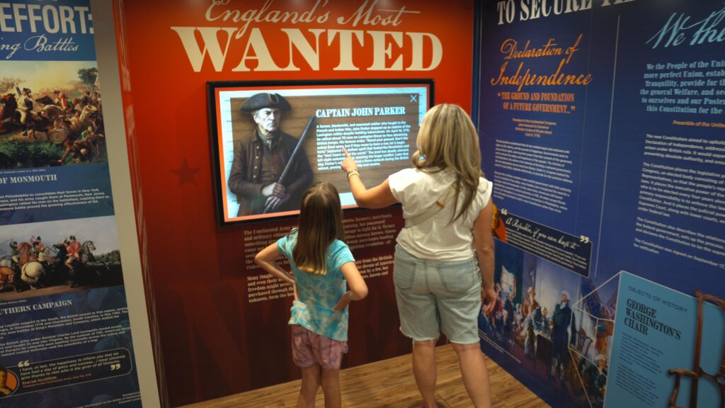 Woman and girl looking at "Wanted" museum display