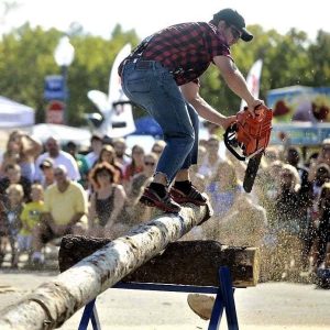 man on log with chainsaw